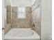 Tiled bathroom with a tub, shuttered window, and decorative accents, offering a relaxing retreat at 307 S Arrawana Ave # 100, Tampa, FL 33609