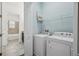 Laundry room featuring a washer, dryer, storage shelf, and convenient access to an adjacent bathroom at 307 S Arrawana Ave # 100, Tampa, FL 33609