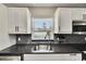 Modern kitchen sink with sleek faucet, granite countertops, subway tile backsplash, and a view of the pool at 4710 Travertine Dr, Tampa, FL 33615