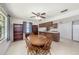 Open dining area features wood table, tile floor, bookshelves, and seamless access to kitchen with white appliances at 6520 Meadowbrook Ln, New Port Richey, FL 34653