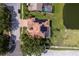 Birds eye view of single-story home with a tile roof, paved driveway, screened lanai, and lush landscaping, pond view at 800 Belted Kingfisher S Dr, Palm Harbor, FL 34683