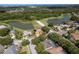 Aerial view of a single-story home with tile roof, two car garage, fountain, and lake view in a wooded, desirable neighborhood at 800 Belted Kingfisher S Dr, Palm Harbor, FL 34683