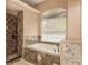 Relaxing bathroom featuring a soaking tub and separate glass shower with decorative stone accents at 800 Belted Kingfisher S Dr, Palm Harbor, FL 34683