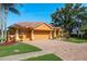 Lovely home features a terracotta roof, two-car garage with a basketball hoop, brick driveway, and tropical landscaping at 800 Belted Kingfisher S Dr, Palm Harbor, FL 34683