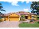 Inviting single-story home with a tile roof, paved driveway, two car garage, and a charming landscaped front yard with a fountain at 800 Belted Kingfisher S Dr, Palm Harbor, FL 34683