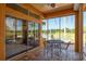 Outdoor patio seating with views of the lake and palm trees from the screened-in lanai at 800 Belted Kingfisher S Dr, Palm Harbor, FL 34683