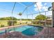 The screened-in pool on brick pavers has views of a palm tree and the lake at 800 Belted Kingfisher S Dr, Palm Harbor, FL 34683