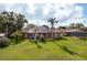 Expansive backyard with lush green lawn, and a screened in lanai with solar panels atop a tile roof at 800 Belted Kingfisher S Dr, Palm Harbor, FL 34683