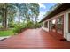 Wide wooden deck, ideal for outdoor entertaining, showcasing exterior details and lush landscaping surrounding the property at 8011 N Mobley Rd, Odessa, FL 33556