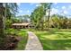 Charming house with a brick pathway, surrounded by lush greenery, flowering plants, and mature trees at 8011 N Mobley Rd, Odessa, FL 33556