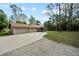 Charming home featuring a multi-car garage, stone accents, and a winding driveway, surrounded by lush greenery at 8011 N Mobley Rd, Odessa, FL 33556