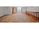 Large living room with carpeted flooring, wooden railing, and window with natural light at 8011 N Mobley Rd, Odessa, FL 33556