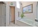 Bright bathroom featuring a soaking tub, tile floors, and an open doorway to another room at 8916 Southbay Dr, Tampa, FL 33615