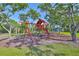 A colorful wooden playground with swings and climbing features surrounded by trees and green space at 8916 Southbay Dr, Tampa, FL 33615