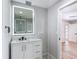 Bathroom with an illuminated mirror over a modern vanity with gold hardware and a shower with glass doors at 10006 N Connechusett Rd, Tampa, FL 33617