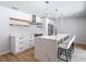 Contemporary kitchen with white cabinetry, open shelving, stainless steel appliances, and a central island with bar stools at 10006 N Connechusett Rd, Tampa, FL 33617