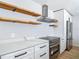 Modern kitchen featuring white cabinets, stainless steel appliances, and open wood shelving at 10006 N Connechusett Rd, Tampa, FL 33617