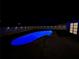 Backyard view of a pool with bright blue lighting, surrounded by a white privacy fence with spotlights at 10006 N Connechusett Rd, Tampa, FL 33617