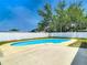 Backyard featuring an in-ground pool, mature trees, and a white privacy fence on a sunny day at 10006 N Connechusett Rd, Tampa, FL 33617