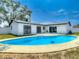 In-ground pool is surrounded by a concrete patio and a white house with black trimmed windows at 10006 N Connechusett Rd, Tampa, FL 33617