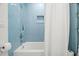 Clean bathroom features blue tiling in the shower/tub and white shower curtain and integrated shower caddy at 1003 W Indiana Ave, Tampa, FL 33603