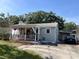 Charming home featuring a covered front porch, red door, gray siding, and mature landscaping at 1003 W Indiana Ave, Tampa, FL 33603