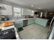Spacious kitchen featuring an apron sink, stainless steel appliances, and stylish aqua cabinetry at 1003 W Indiana Ave, Tampa, FL 33603