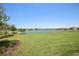 Beautiful community view featuring a scenic lake, lush green lawn, and walking path on a bright, sunny day at 10111 Tuscan Sun Ave, Riverview, FL 33578