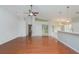 Bright living room featuring gleaming hardwood floors, a ceiling fan, and a kitchen view at 11741 Teapot Ct, Spring Hill, FL 34609