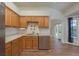 Well-lit kitchen offers stainless steel dishwasher, oak cabinets, and a view to the outdoors at 1246 Ocean Reef Rd, Wesley Chapel, FL 33544