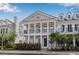 Two-story townhome with white columns, front porch, and dark accents, set amidst lush, manicured landscaping at 135 Commonwealth N Ct, St Petersburg, FL 33716