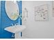 Stylish powder room features vessel sink with charming fixtures, blue paneling and artistic decor at 135 Commonwealth N Ct, St Petersburg, FL 33716