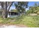 View of the overgrown backyard with a dilapidated screen room at 1506 E Poinsettia Ave, Tampa, FL 33612