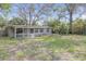 Exterior view of house with screen porch and overgrown front yard at 1506 E Poinsettia Ave, Tampa, FL 33612