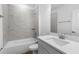 Modern bathroom with marble-look tile, white fixtures, vanity and shower-tub combo at 16247 Little Auk Rd, Weeki Wachee, FL 34614