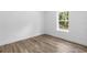 Bright bedroom with wood-look floors, white walls and trim, and a large window at 16247 Little Auk Rd, Weeki Wachee, FL 34614