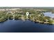 Aerial view of a waterfront property showcasing its location, dock, and the surrounding lake and lush landscape at 16315 Lonely Ln, Odessa, FL 33556