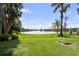 Lush backyard with scenic lake views, mature trees providing shade, and a brick fire pit area for cozy evenings outdoors at 16315 Lonely Ln, Odessa, FL 33556