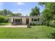 Welcoming home exterior featuring a manicured lawn, modern porch seating, and a charming front door with wreath detail at 16315 Lonely Ln, Odessa, FL 33556