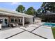 Covered patio with outdoor seating leads to a pool and paved backyard area at 16315 Lonely Ln, Odessa, FL 33556
