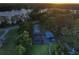 Aerial sunset view of a lakefront property with a main house and guest house surrounded by lush trees at 16603 Hutchison Rd, Odessa, FL 33556