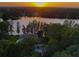 Stunning aerial view of lakeside home surrounded by lush trees and landscaping at sunset at 16603 Hutchison Rd, Odessa, FL 33556