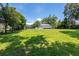 Backyard with lush grass and mature trees with a view of the home's various outbuildings at 16603 Hutchison Rd, Odessa, FL 33556