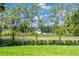 Scenic backyard view of a calm lake through a black metal fence and lush green landscape at 16603 Hutchison Rd, Odessa, FL 33556