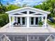 Charming balcony featuring double doors, white columns, and a cozy seating area with cushions and a table at 16603 Hutchison Rd, Odessa, FL 33556