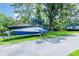 Property featuring a trailer boat parked on a driveway beside a well-maintained lawn and nearby structure at 16603 Hutchison Rd, Odessa, FL 33556