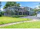View of the property with screened in patio and well-maintained lawn and landscaping at 16603 Hutchison Rd, Odessa, FL 33556