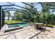 A view of the screened-in pool with hot tub and lush landscape perfect for relaxation and enjoyment at 16603 Hutchison Rd, Odessa, FL 33556