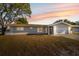 Charming single-story home featuring an attached garage and a well-manicured lawn at sunset at 1700 Ironwood E Ct, Oldsmar, FL 34677
