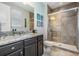 Bathroom with a granite countertop, dark cabinets, and a tiled shower with glass door at 17724 Daisy Farm Dr, Lutz, FL 33559
